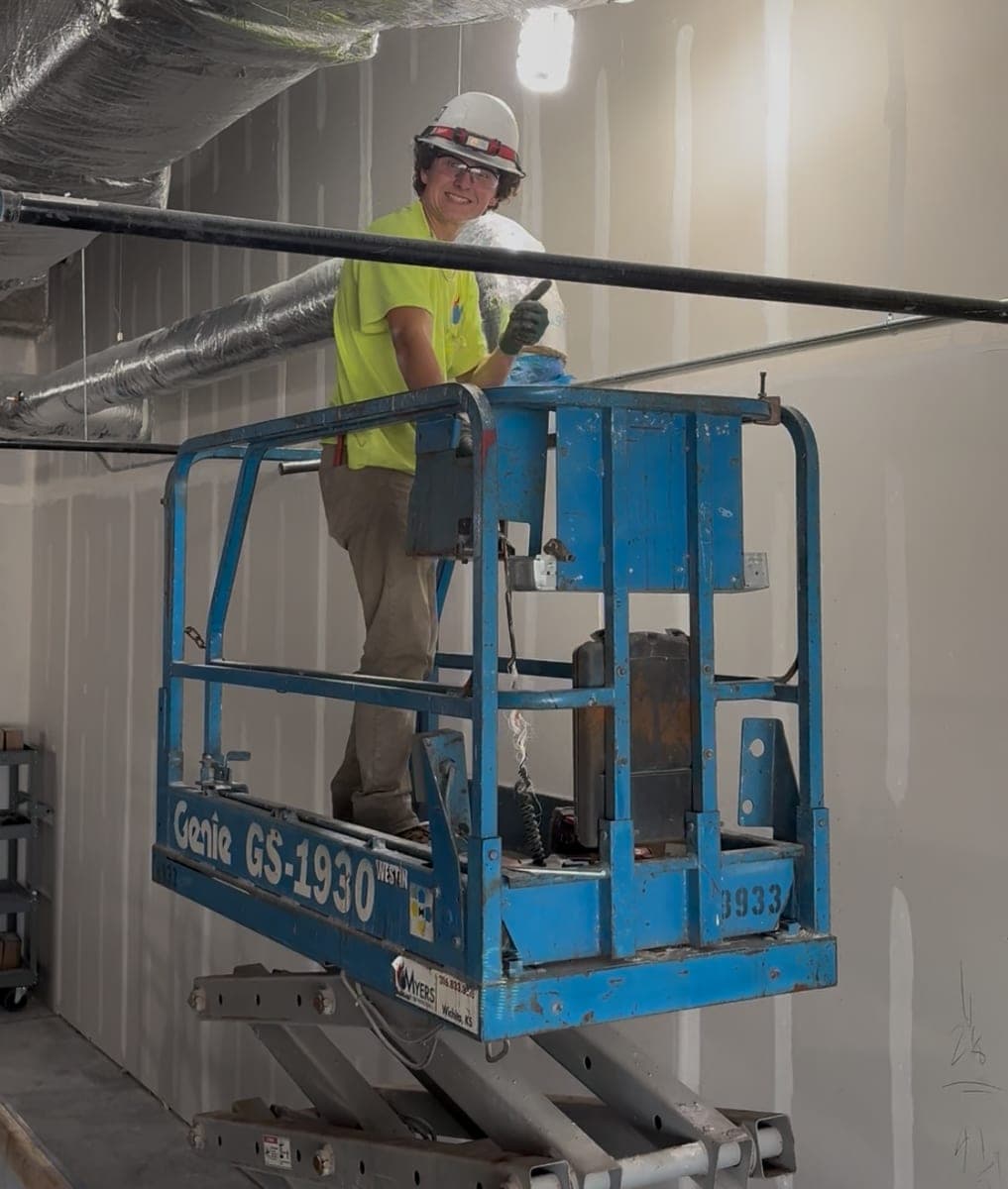 Myers AFP foreman installing overhead fire sprinkler pipe from a lift on a Kansas job site